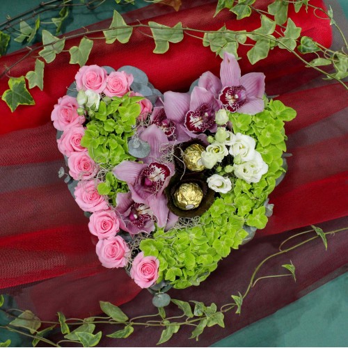Σύνθεση καρδιά με σιμπίντιουμ, τριαντάφυλλα, ορτανσία και σοκολατάκια